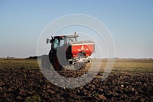 Tractor spreading artificial fertilizers in field