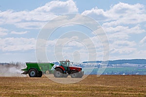 Tractor spreading fertilizer on grass field. Agricultural work photo