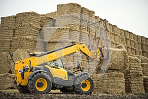 Tractor stacks bales of hay on the field