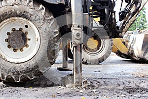 Tractor strong outrigger stabilizing legs extended to stabilize and steady state when digging the soil under the road repair.