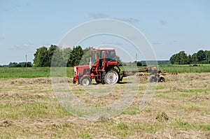 Tractor ted hay dry grass in agriculture field