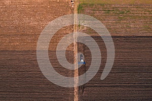 Tractor with tiller equipment plowing farmland soil, aerial shot photo