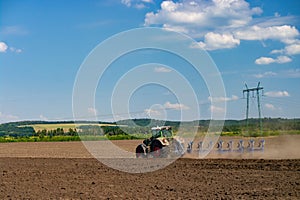 Tractor with a towed plow cultivates the plowing of the field before the autumn sowing photo