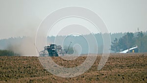 A tractor with a trailed seed drill working in the field. Planting of crops