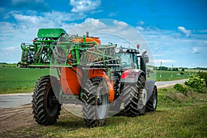 Tractor with trailed sprayer, near winter crop field, spring crop fertilizers, beautiful sky