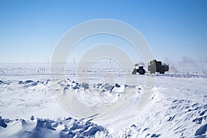 Tractor with trailer driving on snowy road.