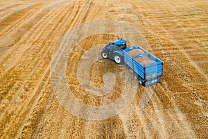 Tractor with a trailer traverses a reaped agricultural field