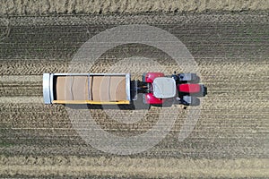 A tractor transports the ripe golden wheat to the grain field harvested by the combine. Agricultural work in summer. Drone