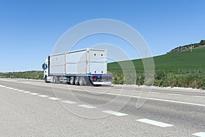 A tractor truck driving with a trailer with some prefabricated construction sheds