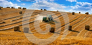 tractor uses a trailed bale machine to collect straw in the field and make round large bales. Agricultural work, hay collection