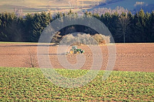 Tractor working on the farm, a modern agricultural transport, a farmer working in the field, fertile land, tractor on a sunset