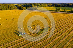 Tractor working in the field with hay to get it dried under the heat of the summer sun. Agriculture field haystack. Landscape with