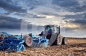 Tractor working in the field at sunset