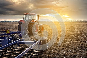 Tractor working in the field on a sunset background