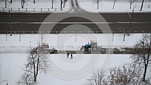 Tractors clean sidewalk from snow. Elderly people letting equipment pass.