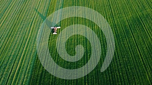 Tractors mow green grass in the fields aerial shot in summer at sunset