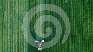 Tractors mow green grass in the fields aerial shot in summer at sunset