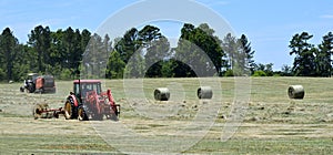 Tractors rolling bales of hay