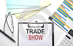 TRADE SHOW text on paper sheet with chart,color paper and calculator