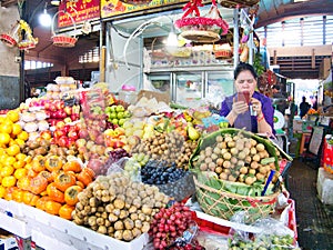 A trader checks her mobiole phone with fruit and vegetables for sale at a market stall in Phnom Penh, Cambodia