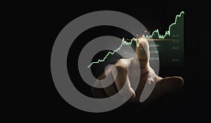 Trader hand touching to stock market graph chart on dark background for technical investment analysis concept