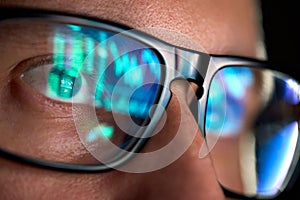 Trader looking at computer screen analyzing trading chart reflecting in glasses.