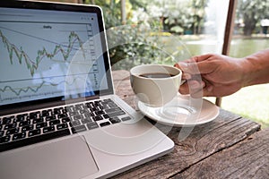 Trader man hand holding a cup of black coffee and analyze tactical move, strategy analysis of stock graph