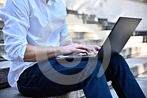 Trader sitting on stairs and typing on laptop