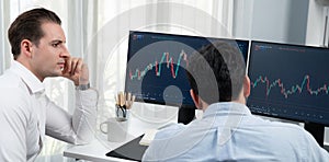 Traders discussing with two market stock screen on panorama view,. Sellable.