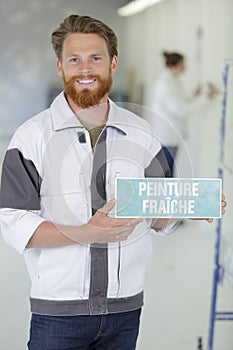 tradesman holding peinture fraiche sign