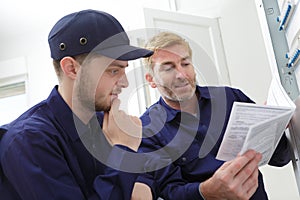 tradesman looking at instruction book by circuit breaker box