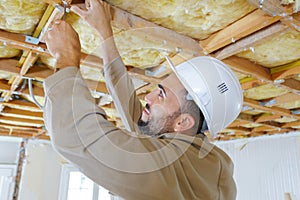 Tradesman using screwdriver on ceiling timbers