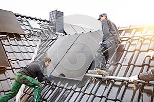 Tradesmen installing solar panels on the roof of a house
