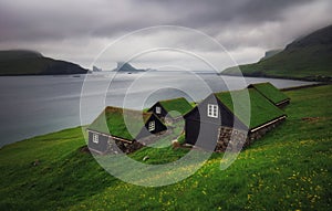 Tradicional faroese grass - covered houses in the village Bour. Drangarnir and Tindholmur sea stacks on background. Vagar island,