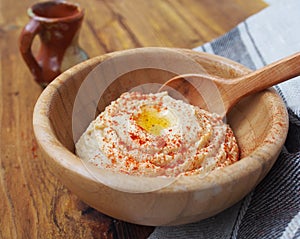 Tradicional oriental hummus with olive oil and paprika in wooden bowl and wooden spoon