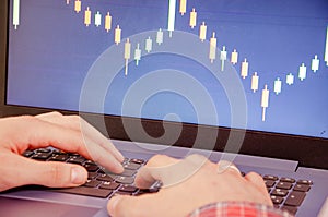 Trading on the exchange. Men`s hands in a plaid shirt at a laptop. On-screen rates, promotions. Schedule. Wins are losses. Part o