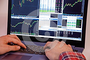 Trading on the exchange. Men`s hands in a plaid shirt at a laptop. On-screen rates, promotions. Schedule. Wins are losses. Part o