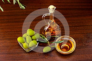 Tradition Crete flavored olive oil with spieces rosemary and pepper, with olives and olive leafs on wooden background.