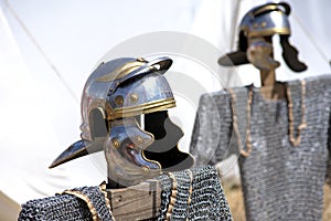 Tradition Roman solder helmet with chain mail underneath on top of wood strut and another helmet and chain mail in the background