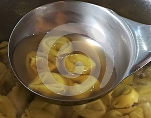 Tortellini al brodo in a soup ladle, close up. Italian food. photo
