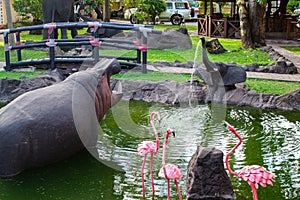 Traditional african handcrafted wooden statues of hipo, elephant and flamingo in a pond of the garden of Cultural Heritage store