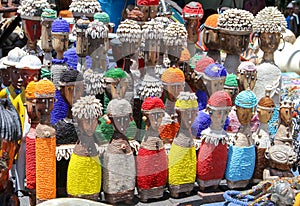 Traditional African wooden handmade dolls with seashells and colorful bead decoration at local craft market, Cape Town, South Afri