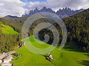 Traditional alpine St Johann church in Val di Funes valley, Santa Maddalena touristic village, Dolomites, Italy. Grass, chapel.