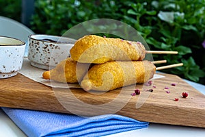 Traditional American street food corn dogs with mustard and ketchup on wooden table.