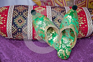 Traditional Arabic green shoes . Arabian oriental green shoes in the Aladdin style . on red beech. pink background . Arabian