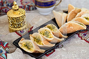 Traditional Arabic kataif crepes stuffed with cream and pistachios, prepared for iftar in Ramadan, oud in gold, on paisley