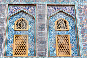 Traditional Arabic mashrabiya window on a tiled wall enclosed with carved wood latticework photo