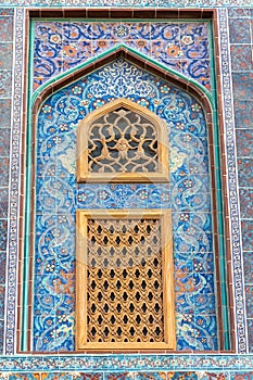 Traditional Arabic mashrabiya window on a tiled wall enclosed with carved wood latticework photo