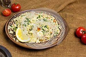 Traditional Arabic salad or Tabbouleh on ceramic plate, healthy vegetarian dish with couscous, tomatoes, parsley, mint