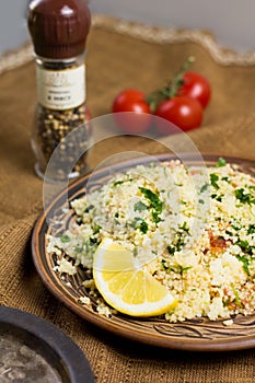 Traditional Arabic salad or Tabbouleh on ceramic plate, healthy vegetarian dish with couscous, tomatoes, parsley, mint